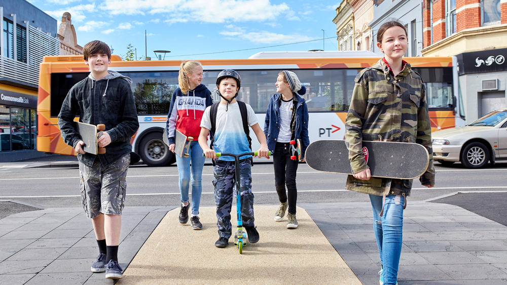 Children with skateboards and scooter near bus