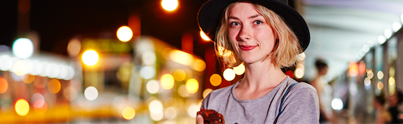 Image of a young woman at a tram stop at night