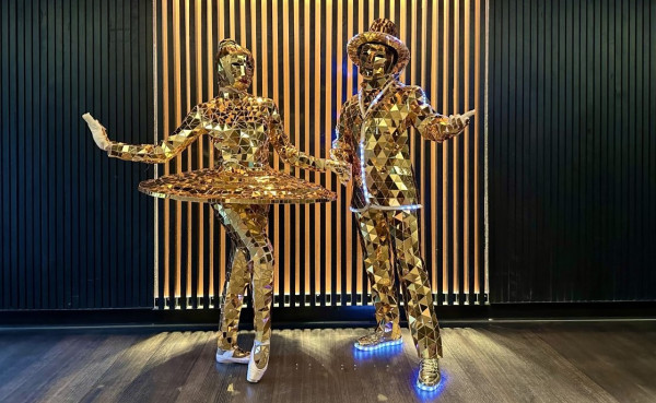 Man and woman dressed in metallic gold outfits.